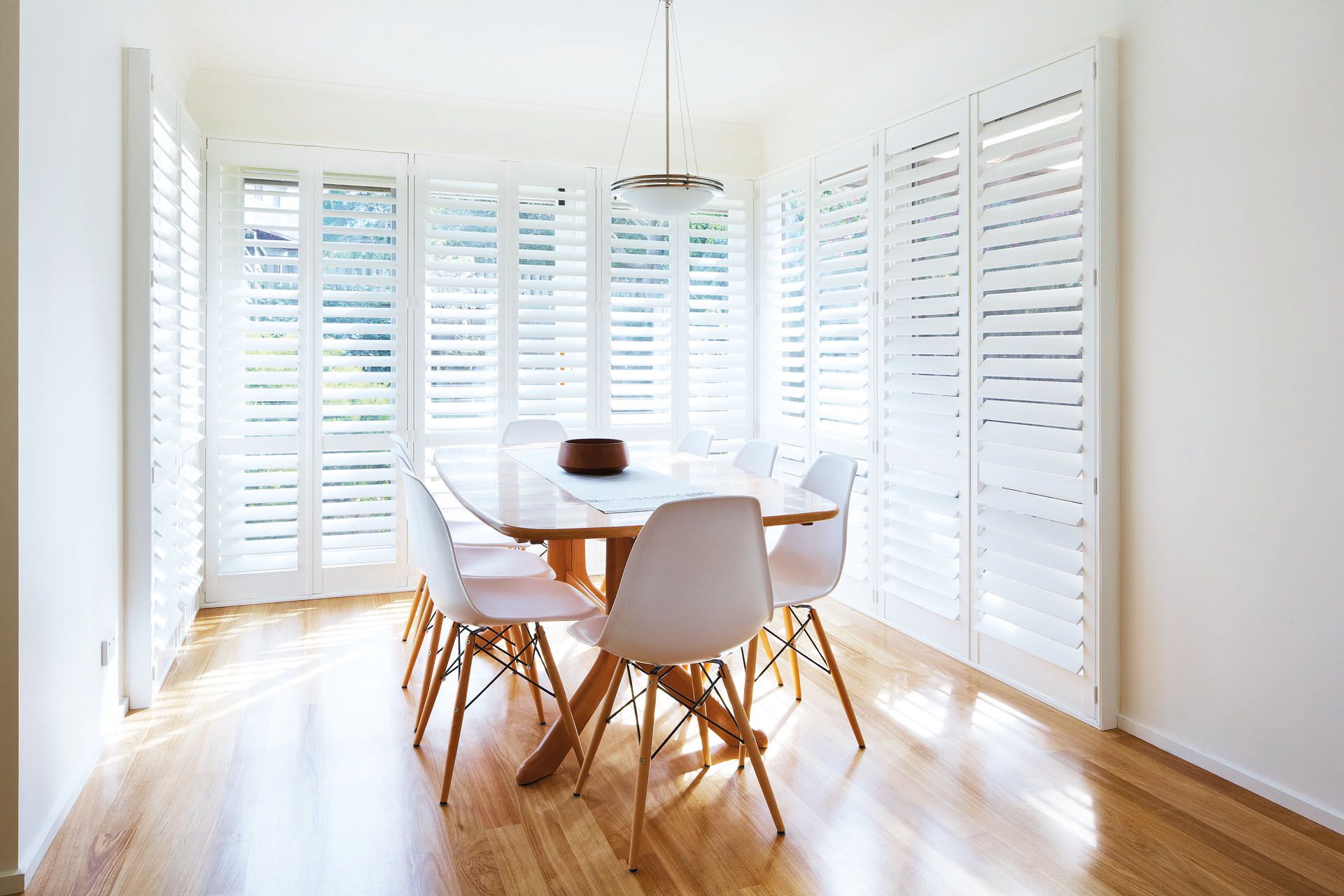 Torquay dining room with wooden floors and large windows covered by blinds.