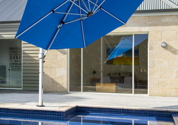 Large blue umbrella giving shade to a backyard pool in Geelong.