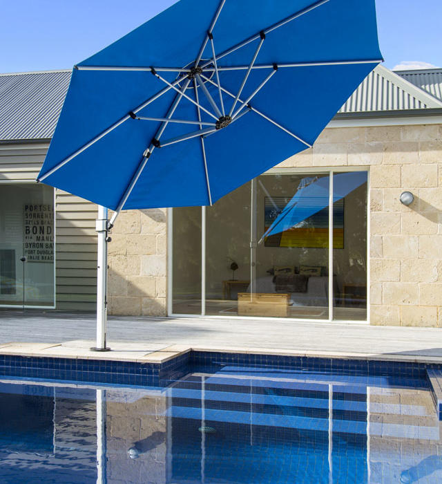 Large blue umbrella giving shade to a backyard pool in Geelong.