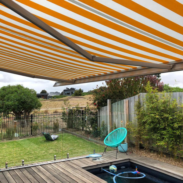Striped exterior motorised blinds covering pool in Torquay backyard.