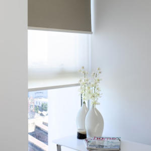 Vase with flowers in front of dark grey and sheer roller blinds in Geelong.