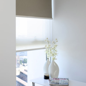 Vase with flowers in front of dark grey and sheer roller blinds in Geelong.